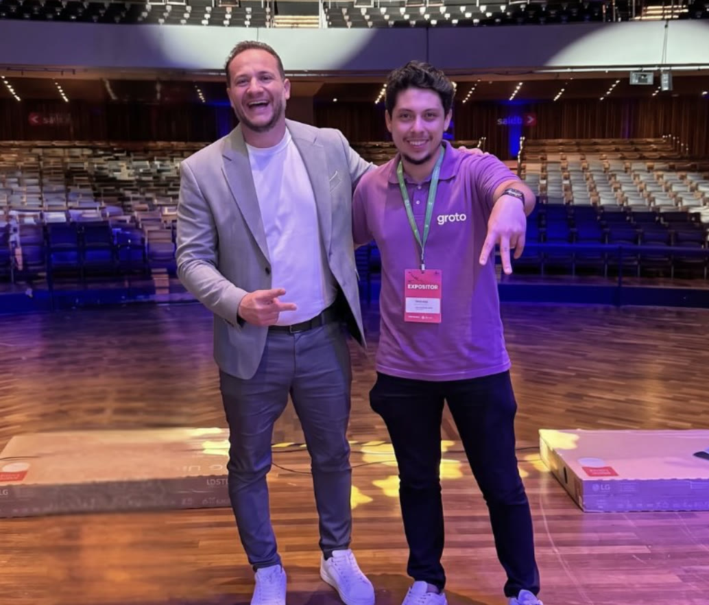 Dois convidados no palco do auditório da Consulfarma 2026, um deles com a camisa da Groto